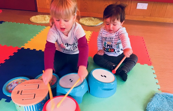 Two kids are playing drums and creating some music.